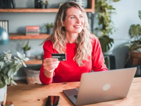 woman sat at laptop with card